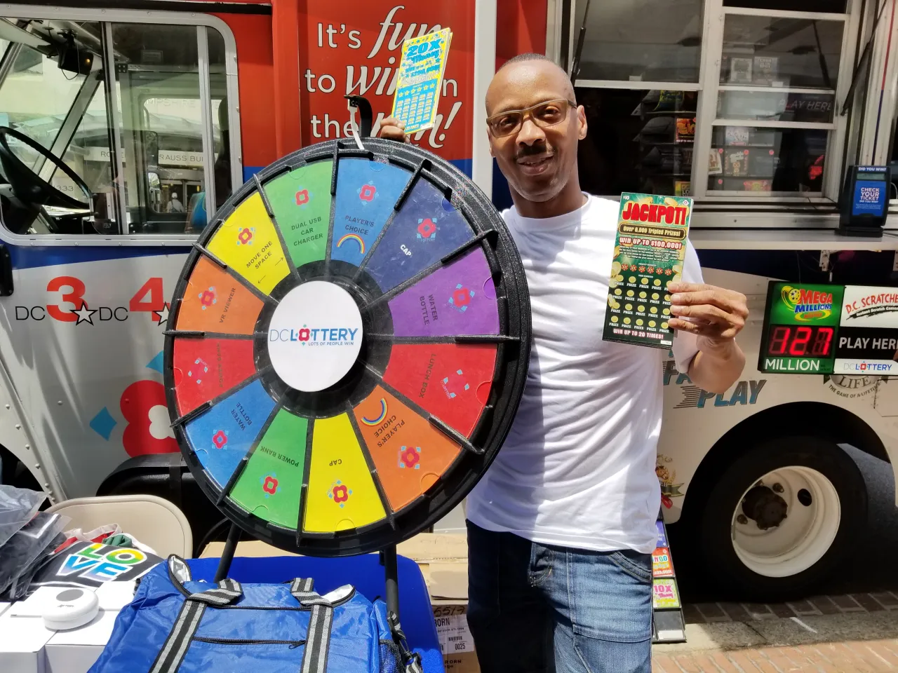 Man holding scratcher and posing with prize wheel