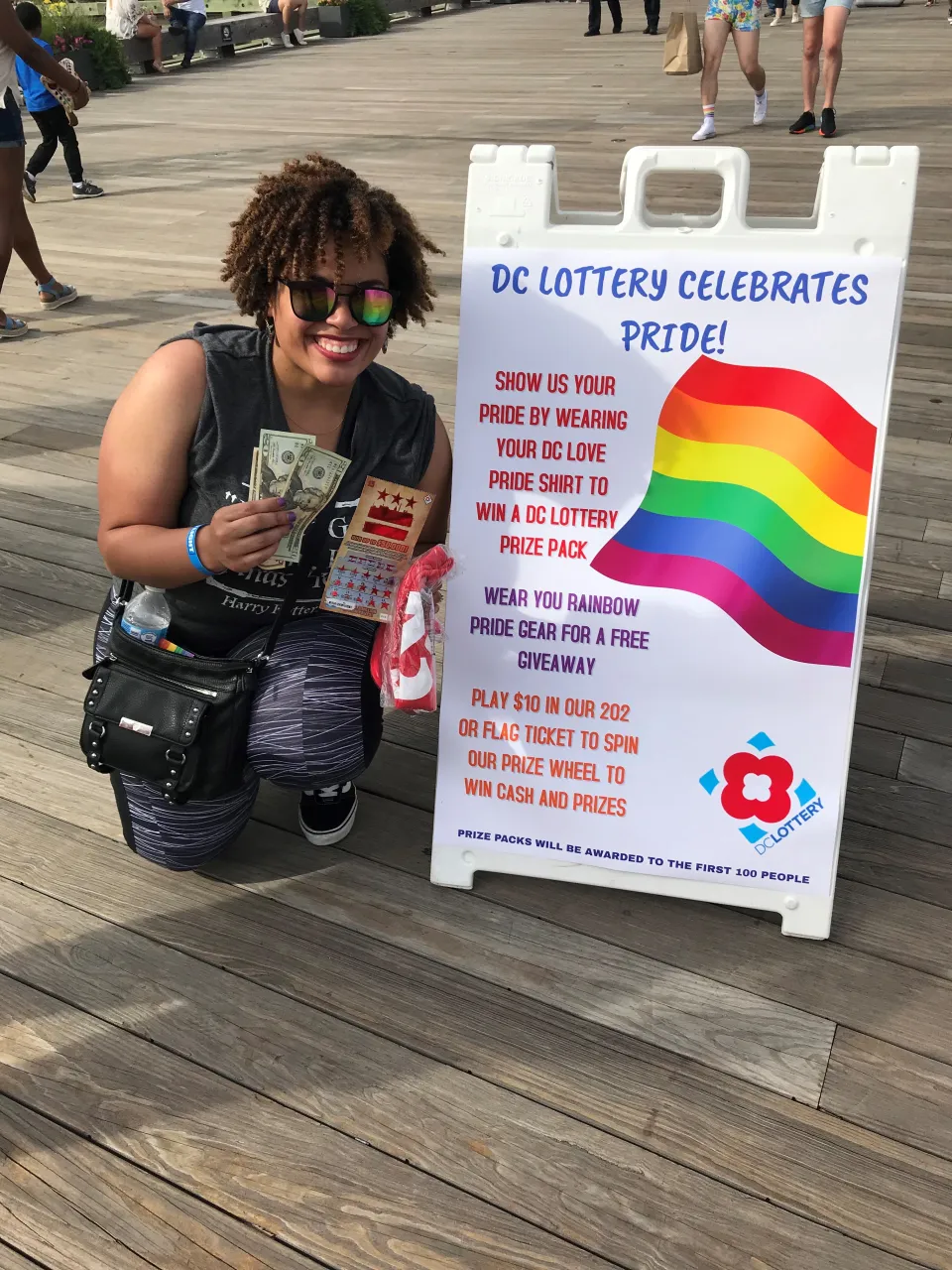 woman posing next to event signage holding scratch tickets