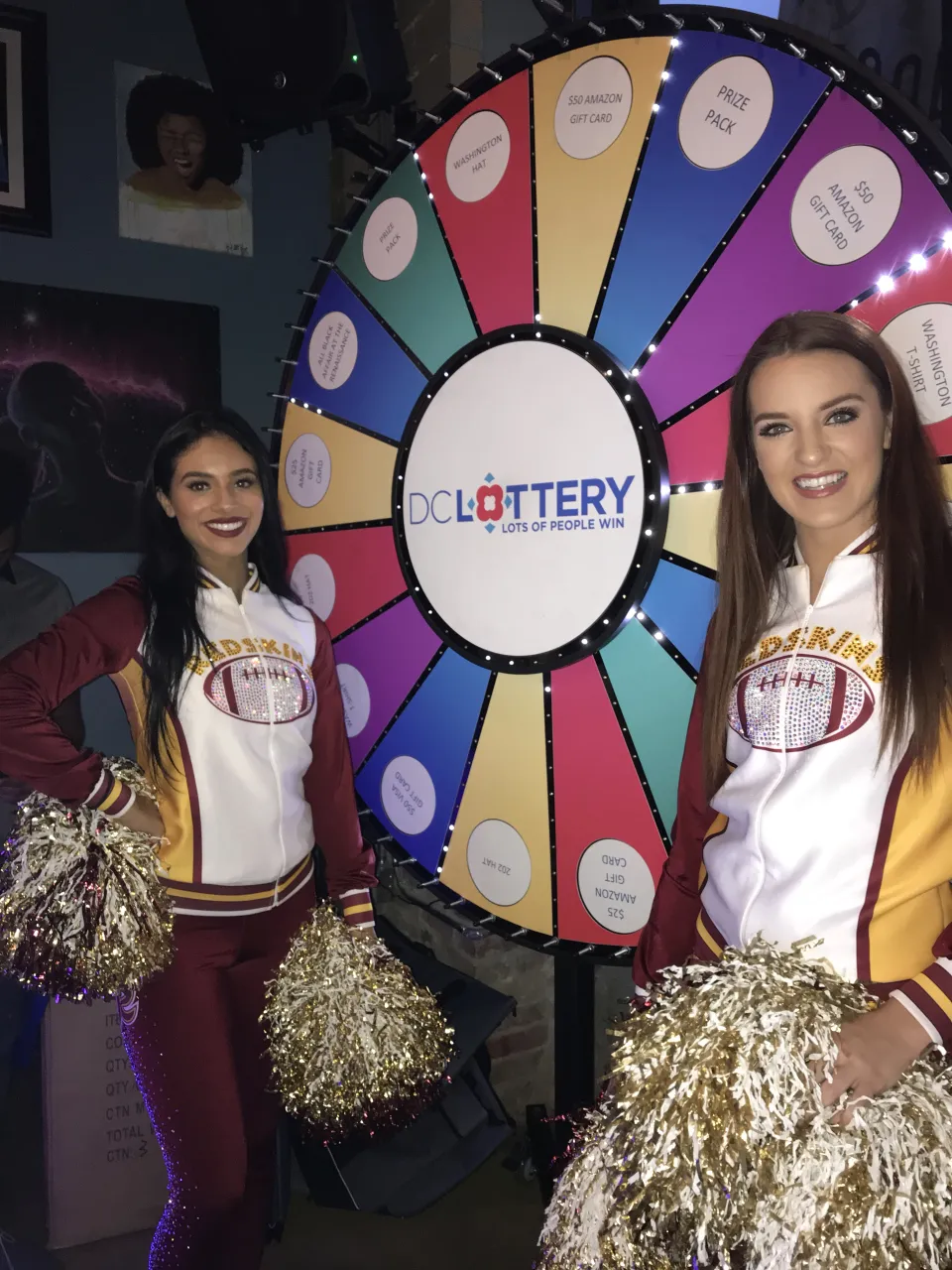 Cheerleaders posing in front of the giant DC Lottery prize wheel